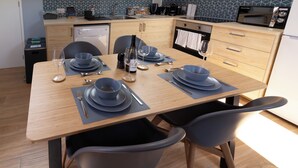 A modern kitchen with a dining area set for four. It includes a dishwasher, microwave, oven, and a sink.