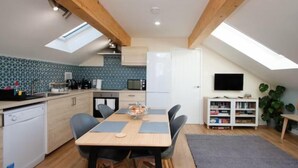 A compact kitchen with a dining area, skylights, and a flat-screen TV.