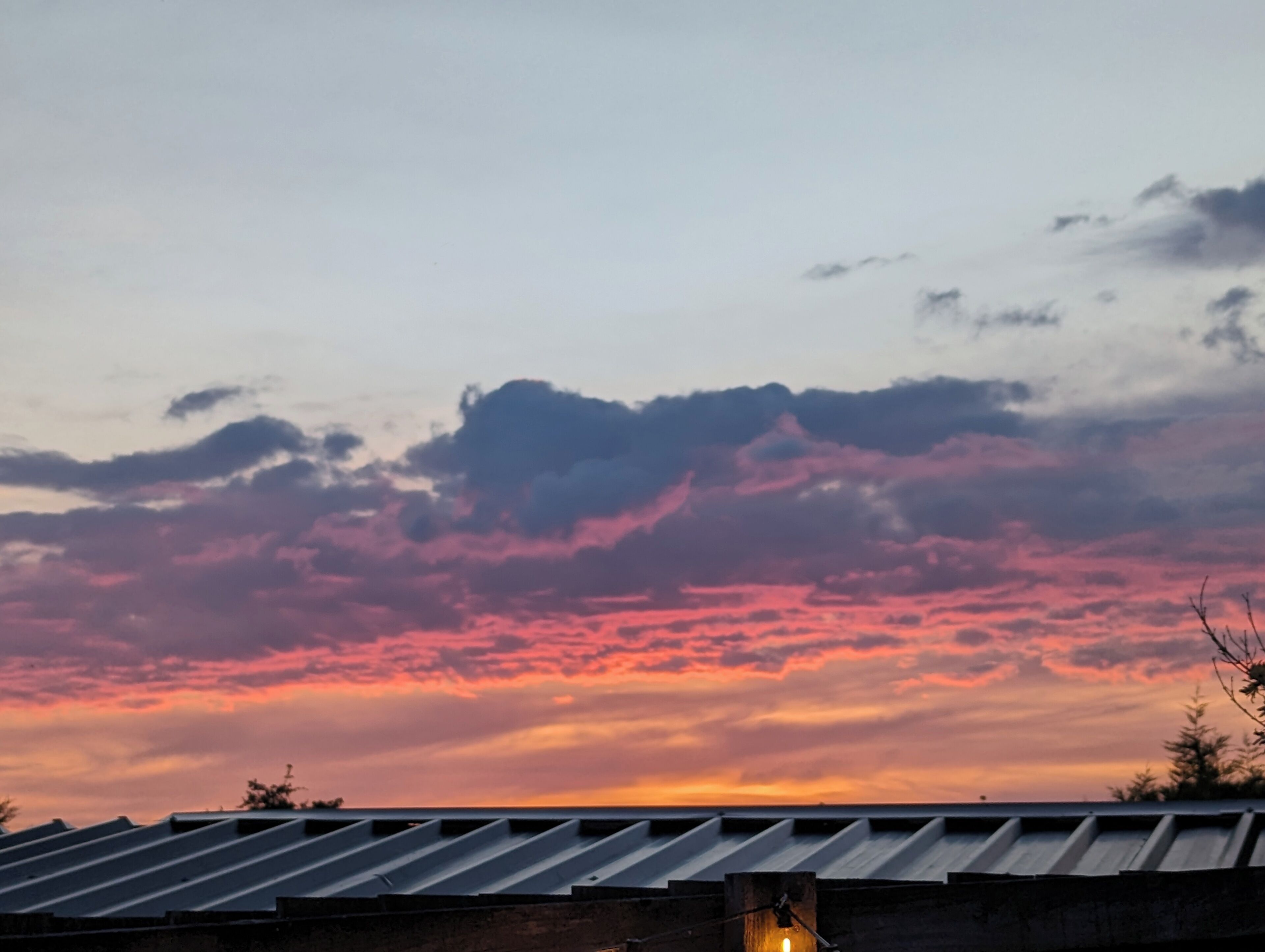 Ein Sonnenuntergang mit einem rosafarbenen und violetten Himmel über einem Gebäude mit einem Metalldach.
