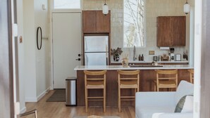 Une cuisine moderne avec des meubles en bois, un réfrigérateur en acier inoxydable et un coin bar avec des tabourets.