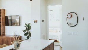 Une cuisine moderne dotée d’un grand îlot central, de meubles en bois, d’un four encastré et d’un luminaire suspendu.