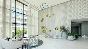 Un vestíbulo amplio con ventanas grandes, un muro con diseño y mobiliario moderno.