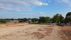 An open field with scattered trees and a few buildings in the background. - Next Door to the Fair RV Park (Spencer)