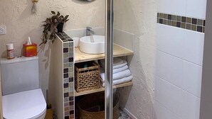 A compact bathroom with a toilet, sink, and shower area. - The House of Evahlia (Creissels)