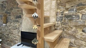 A modern interior with a stone wall, wooden shelves, and a white entertainment unit. - The House of Evahlia (Creissels)