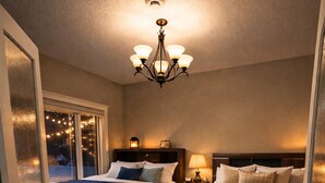 Ein Schlafzimmer mit zwei Betten, einer Chandelüstere und Blick durch eine Glastür.