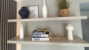 A shelf with decorative items including books, a beaded necklace, and vases.