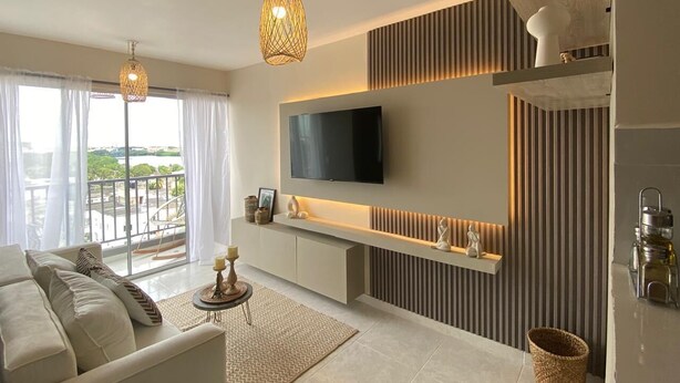 A modern living room with a sofa, TV, and decorative items.