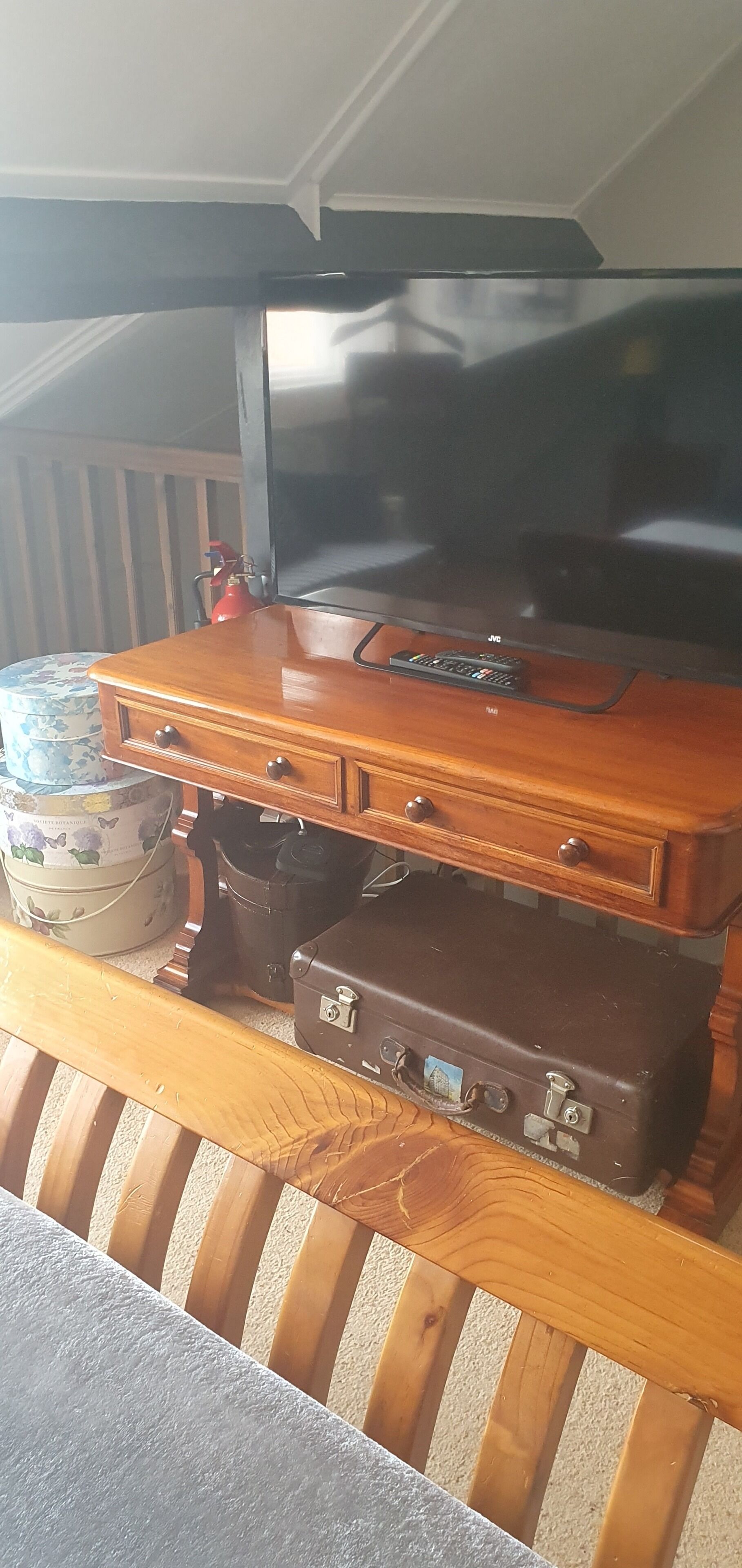A wooden bench with a television on top of a suitcase.