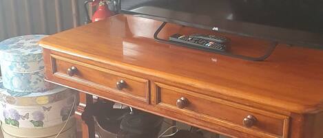 A wooden bench with a television on top of a suitcase.