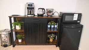 Una kitchenette equipada con cafetera, hervidor, microondas y refrigerador.
