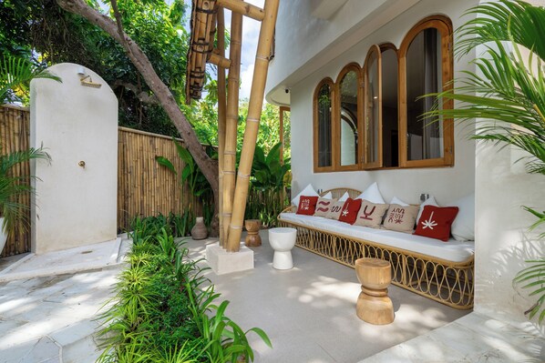 A serene outdoor seating area with a white bench, wooden accents, and lush greenery.