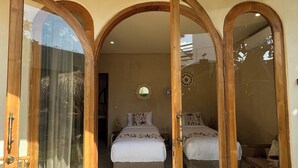 Ein Schlafzimmer mit zwei Betten, einem großen Spiegel und einer Holztür, die sich aufschieben lässt.