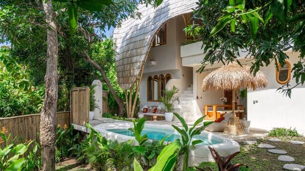Ein modernes Haus mit Swimmingpool, umgeben von üppiger Vegetation und einem Holzzaun.