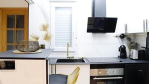 Cocina compacta con encimera negra, electrodomésticos de acero inoxidable y diseño moderno.