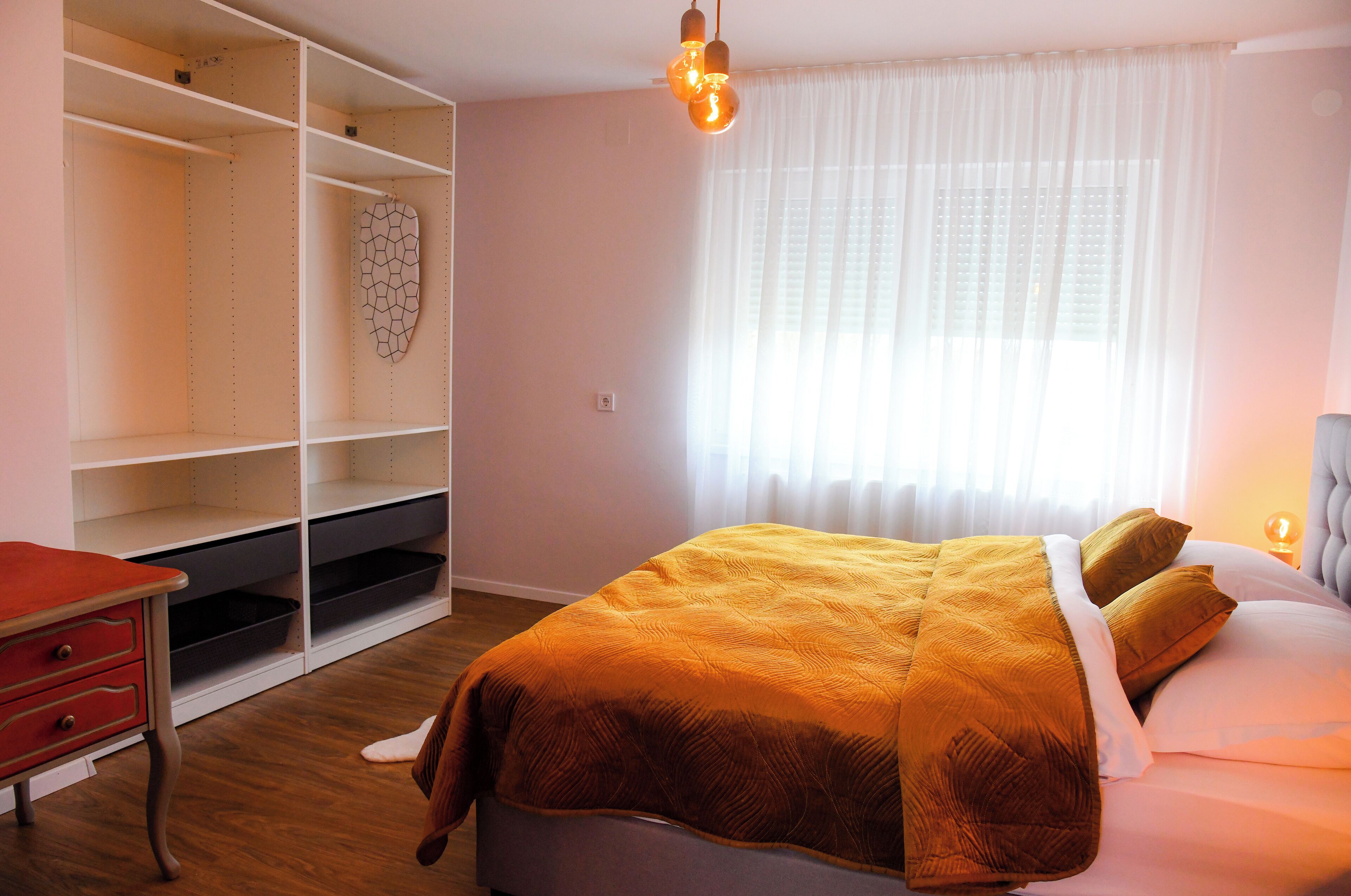 Un dormitorio con cama, armario y escritorio.