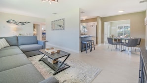 A modern living room with a sectional sofa, a coffee table, and a dining area with a table and chairs. - Private HEATED Pool • Newly Renovated • 5 minutes to the Beach (Seminole)