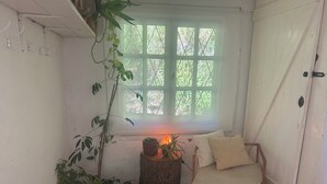 A cozy room with a window, a chair, and several potted plants.