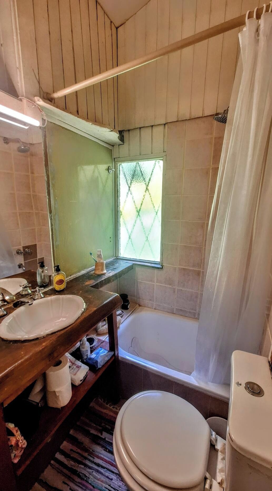 Un baño con tocador de madera, lavamanos, inodoro y bañera.