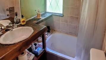 Un baño con tocador de madera, lavamanos, inodoro y bañera.