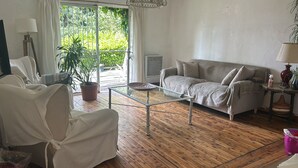 A living room with a sofa, a glass coffee table, a potted plant, and a lamp.