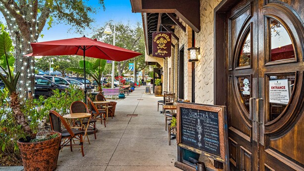 An outdoor seating area with tables and chairs, a red umbrella, and a sign for 'Chocolate Maya'. - GUEST HOUSE w/ PRIVATE ENTRANCE & PATIO for rent in Gulfport, FL (Gulfport)
