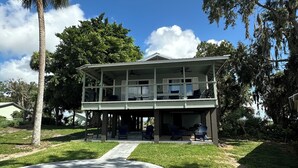 A two-story house with a covered porch, a pathway leading to the entrance, and surrounding greenery.
