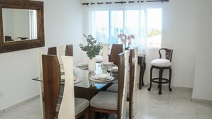 Un comedor con una mesa de vidrio, sillas de madera y un florero con flores.