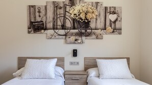 A hotel room with two beds, a wooden headboard, a wall-mounted artwork, and a bedside table. - Hospital Cruces Metro Bec (Barakaldo)