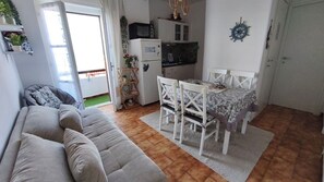 Un espacio habitable compacto con sofá, mesa de comedor y kitchenette.