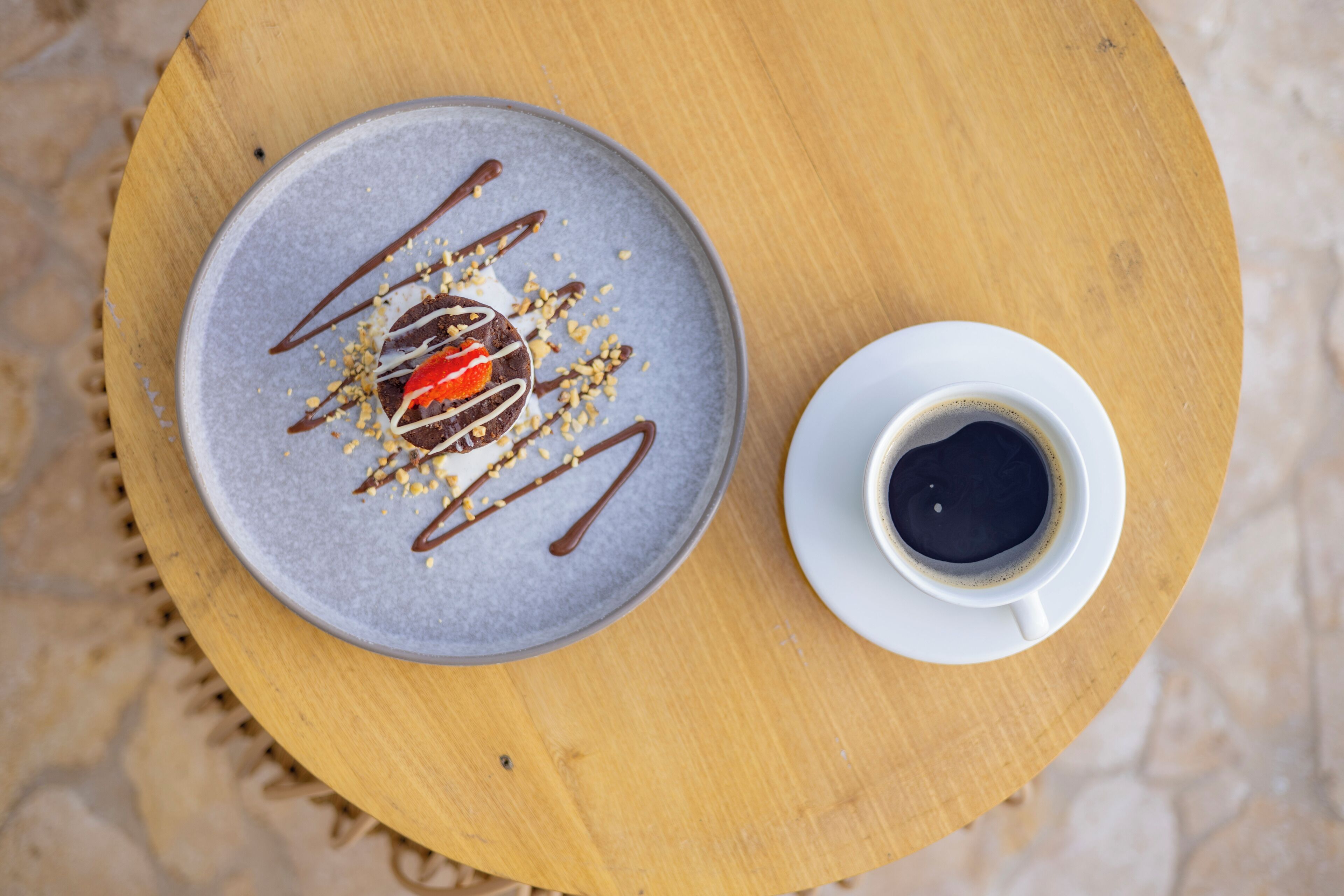 A dessert on a plate with a cup of coffee on a wooden table.