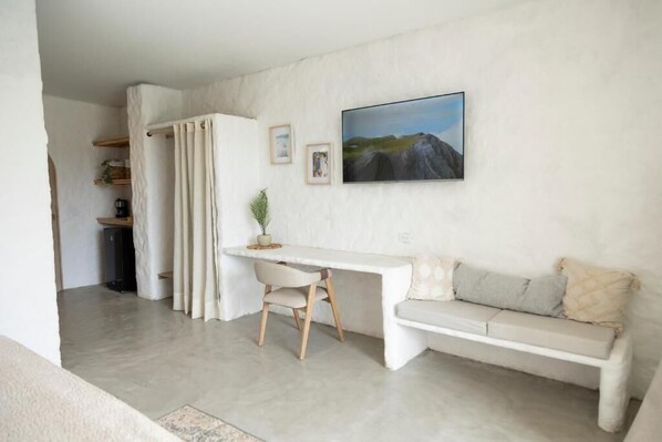 A minimalist living room with a white sofa, a white desk, and a large painting on the wall. - MYLOS Hotel Boutique (Guatapé)