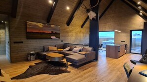 Ein modernes Interieur mit Holzboden, einer großen Couch, einem Esstisch und Blick ins Freie.