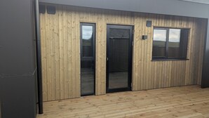 Ein modernes Gebäude mit Holzfassade, zwei großen Schiebegläsern und einem kleinen Fenster.