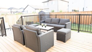 An outdoor patio with wicker furniture, a small table, and a view of residential buildings in the background.