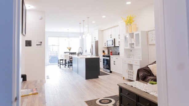 A modern kitchen with white cabinets, a central island, and pendant lighting.
