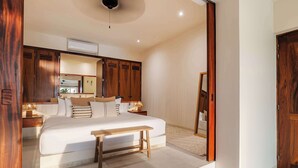 A bedroom with a large bed, wooden wardrobe, bedside tables, a bench, and a ceiling fan. - Ground-Floor Ocean-View Villa with Private Plunge (Zihuatanejo)