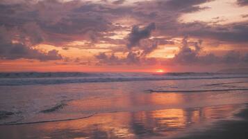 Una playa al atardecer con olas y nubes.