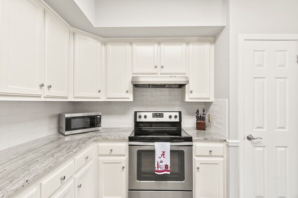 A kitchen with white cabinets, a stainless steel stove, and a microwave.