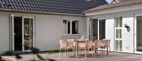 A patio with a table and chairs, a small window, and a door.