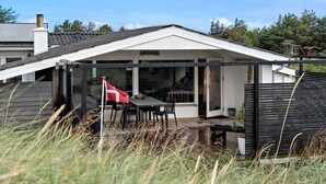 Un patio techado con mesa y sillas, una bandera y una terraza de madera.