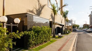 A modern building with a marble facade, a paved sidewalk, and a bench. - Apartments in the Turquesa Building - Balneario Picarras - RTS (Picarras)