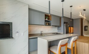 A modern kitchen with a central island, bar stools, and pendant lighting. - Apartments in the Turquesa Building - Balneario Picarras - RTS (Picarras)