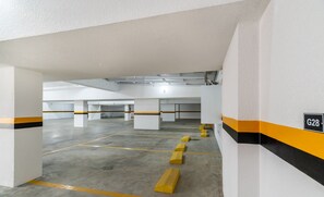 An empty parking garage with white walls and yellow and black stripes, featuring a sign labeled "G28". - Apartments in the Turquesa Building - Balneario Picarras - RTS (Picarras)