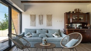 A modern living room with a sofa, two wicker chairs, a coffee table, and a wooden cabinet. - 2 bedroom cozy home in Brodani (Brodani)
