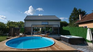 Una casa moderna con piscina, mobiliario de exterior y jacuzzi.