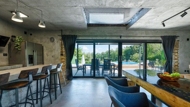 Una cocina moderna con barra, amplios ventanales y vistas a una piscina exterior.