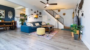 A modern living room with a blue sofa, wooden coffee table, and a staircase leading to another level.