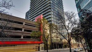 Ein modernes Hochhaus mit Glasfassade, umgeben von Bäumen und einer Tiefgarage.
