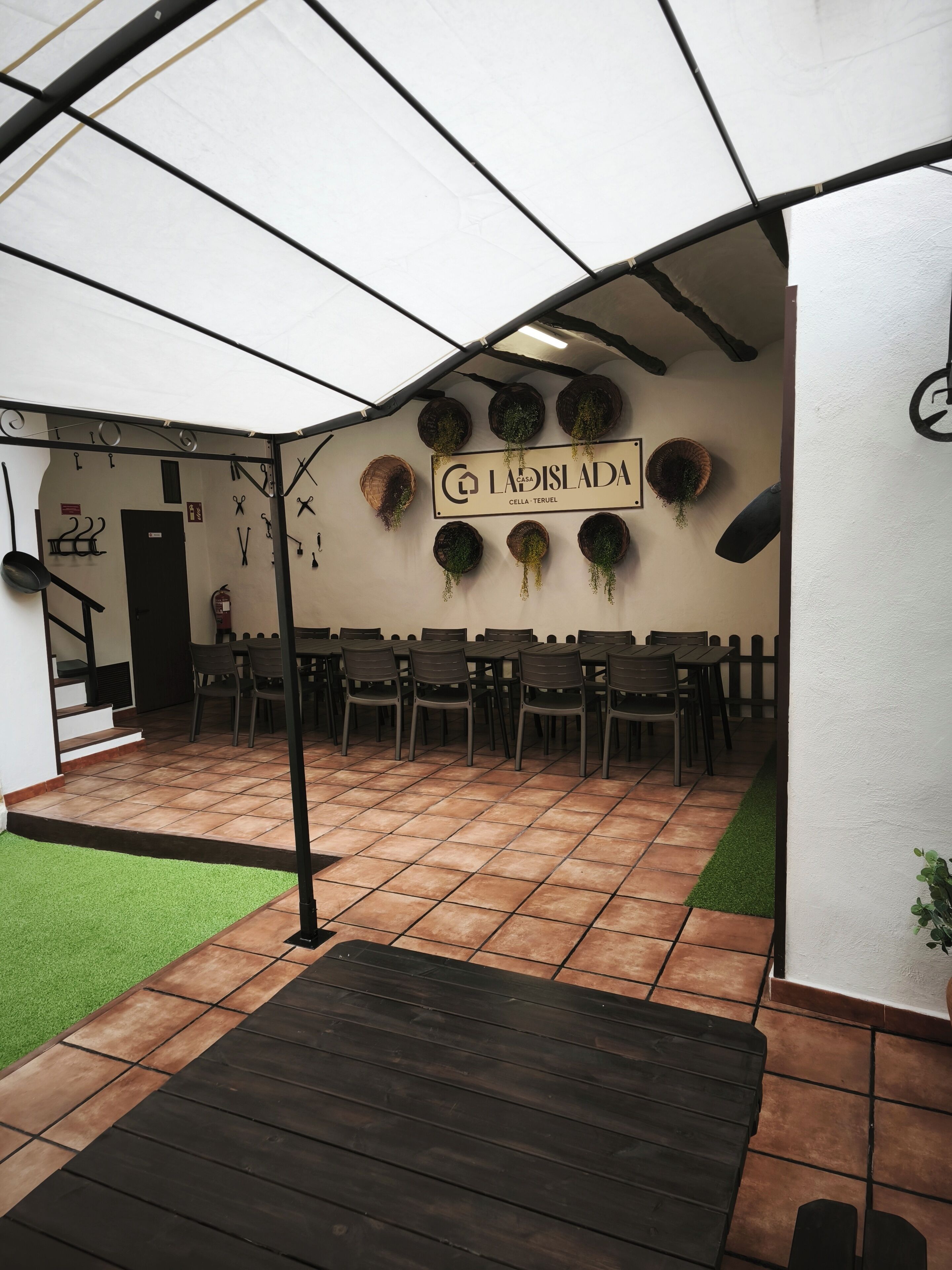 An indoor patio area with a tiled floor, a wooden deck, and a sign reading 'LADISLADA CELHA TERUEL'.